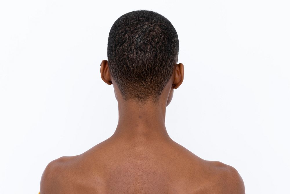 Black woman with shaved head facing the wall 