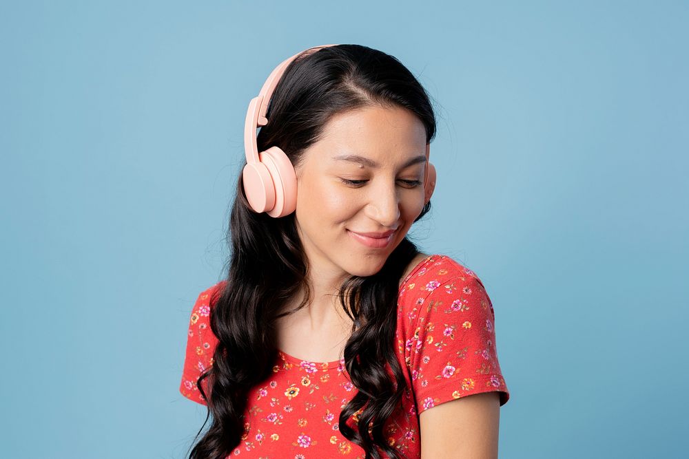 Cheerful woman listening to music with a headset on blue background