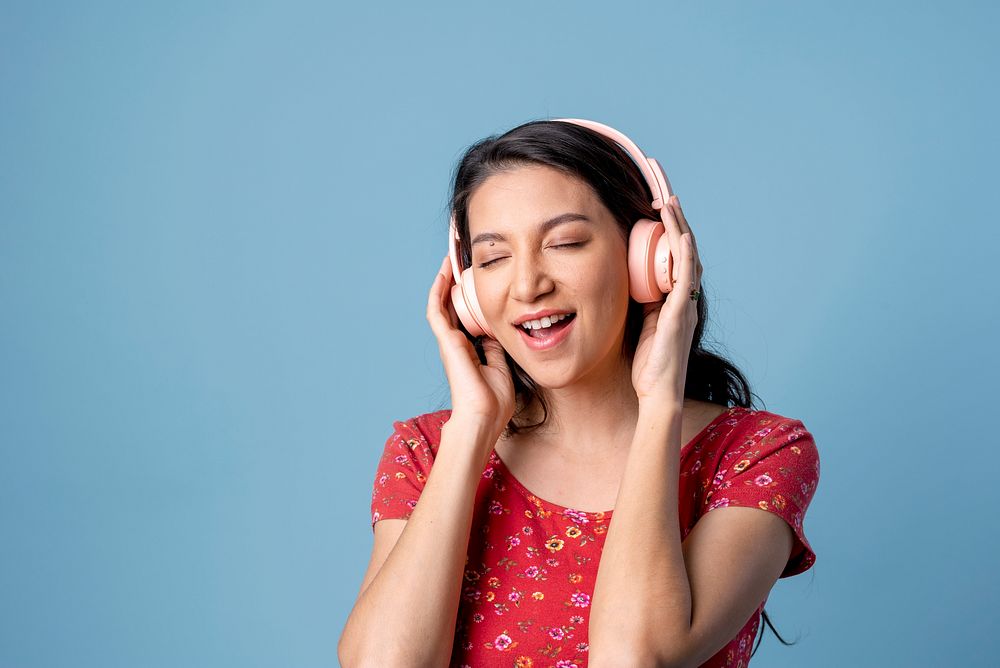 Cheerful woman listening to music with a headset on blue background