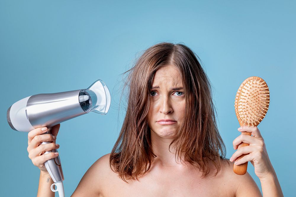 Woman blow drying her messy hair 