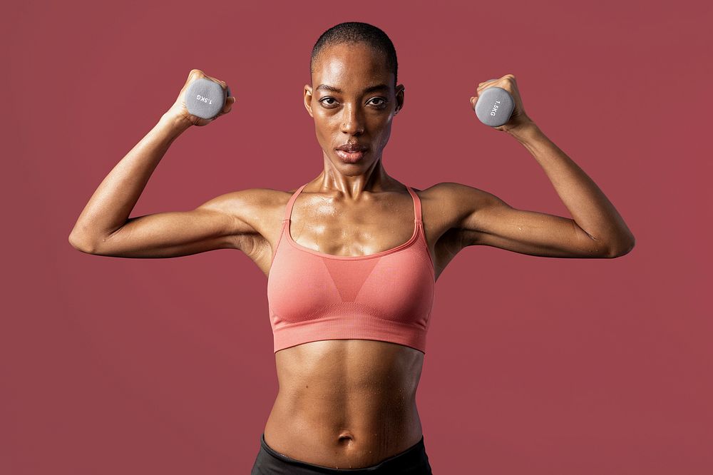 Active black woman lifting dumbbells on red background mockup