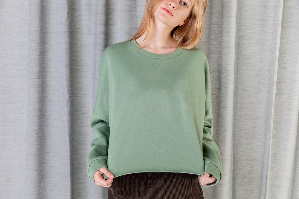 Smart woman wearing green sweater by a curtain