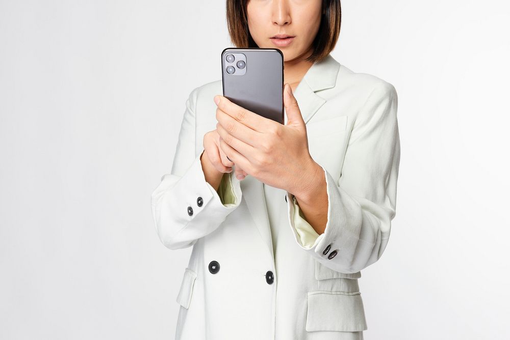 Businesswoman in a white suit holding smartphone