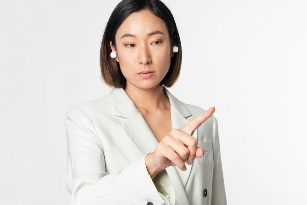 Businesswoman with smart earbuds pointing put her finger