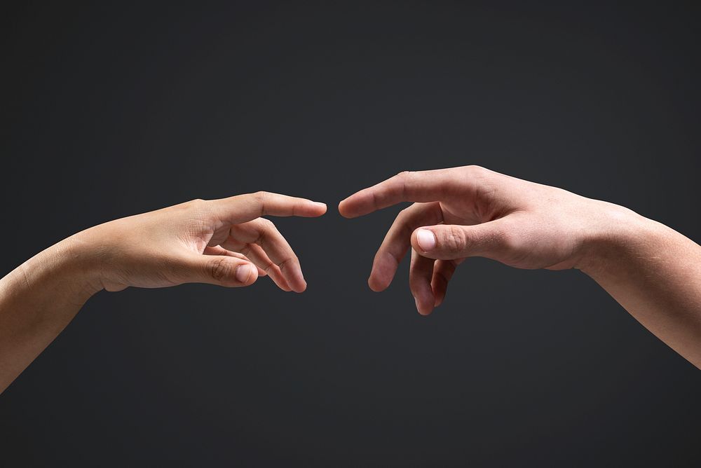 Human hands reaching for each other black background