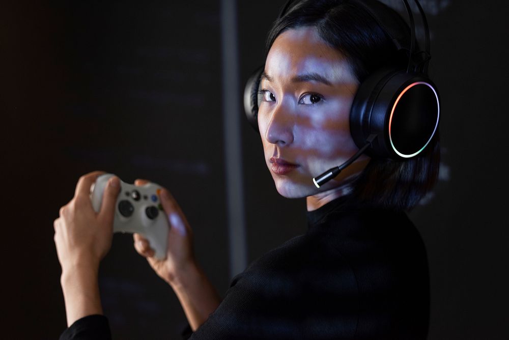 Woman in headset playing game with wireless controller