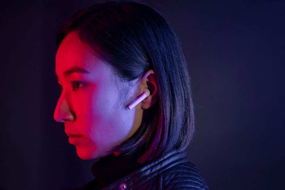 Woman with wireless earbuds in neon light