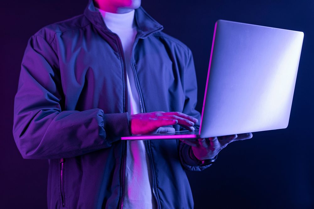 Man using laptop in neon light