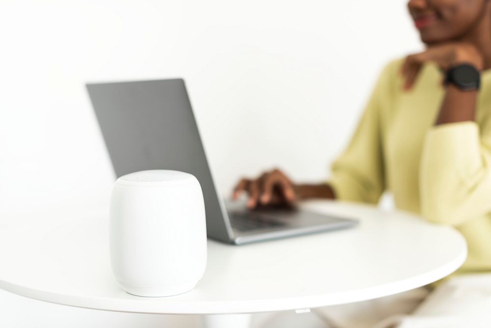 Smart speaker next to laptop with a woman
