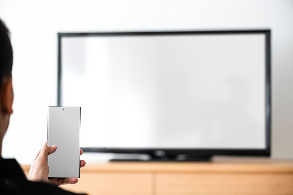 Man turning on smart TV with his smartphone