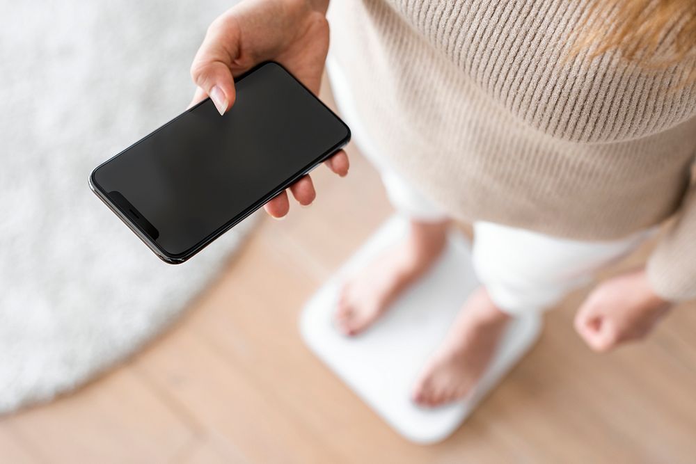 Woman using smartphone on weighing scale innovative technology