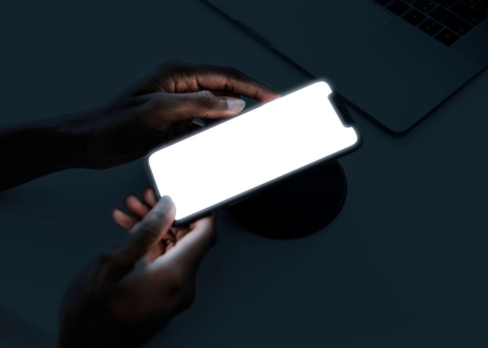 Smartphone glowing screen mockup psd with wireless charger in the dark