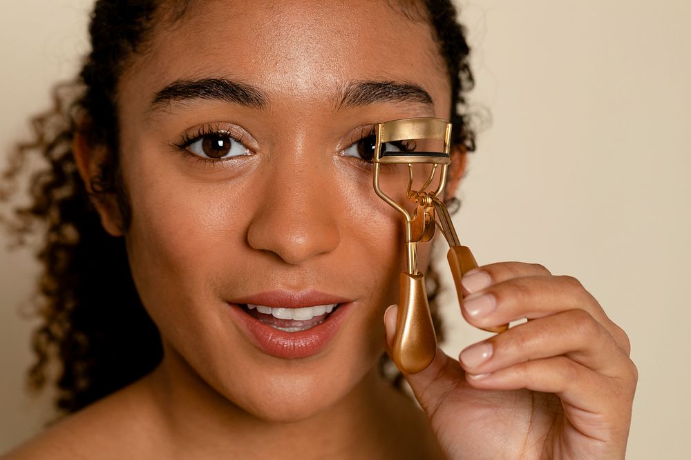 Woman using eyelash curler makeup tool