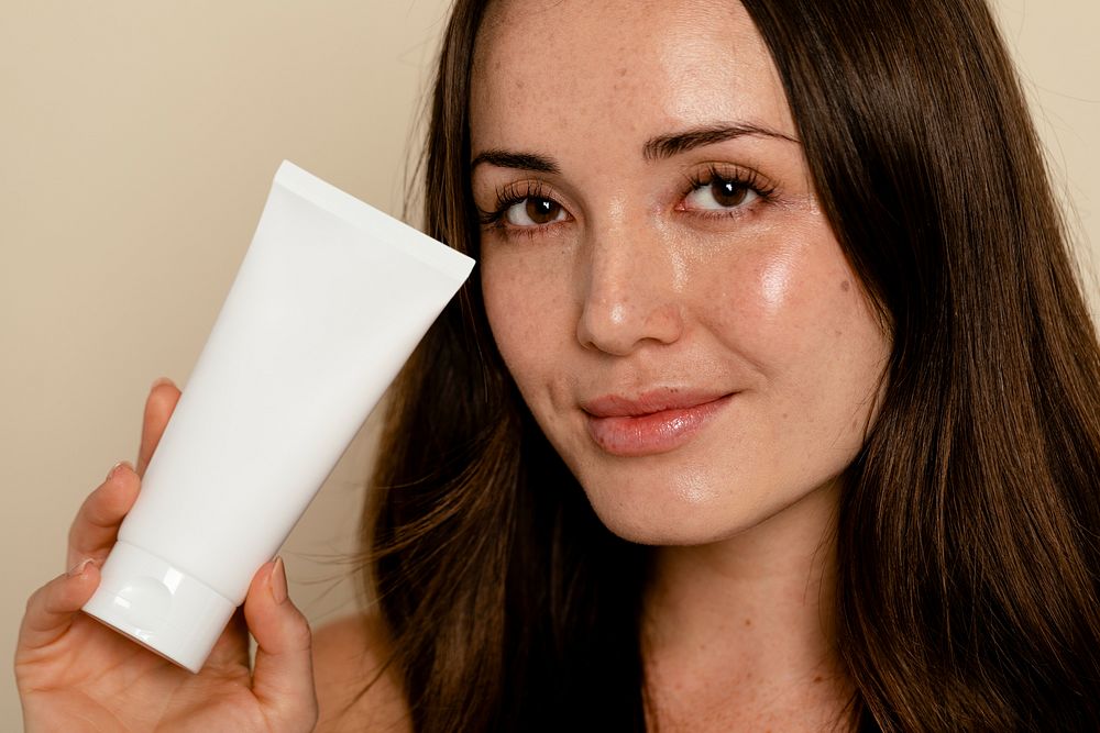 Woman holding face moisturizer tube