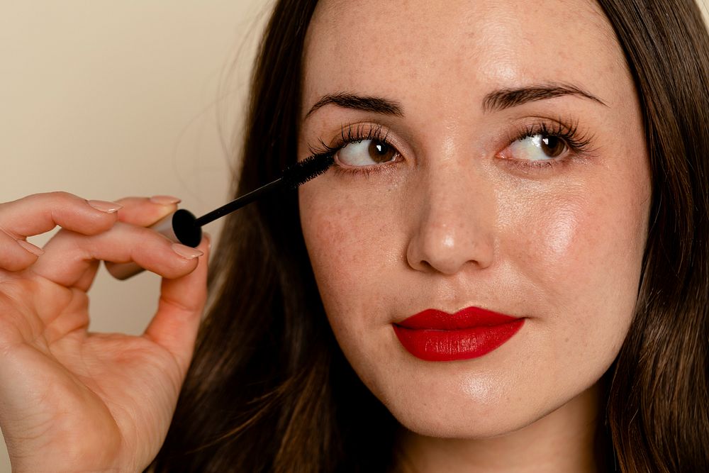 Woman applying mascara to eyelashes