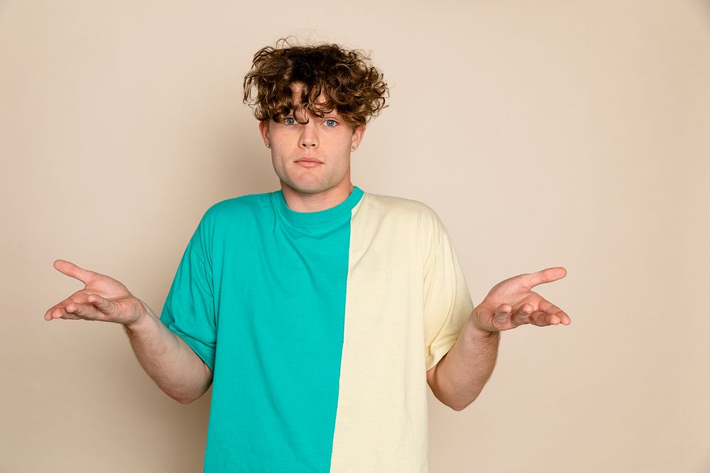 Young man acting confused, beige background