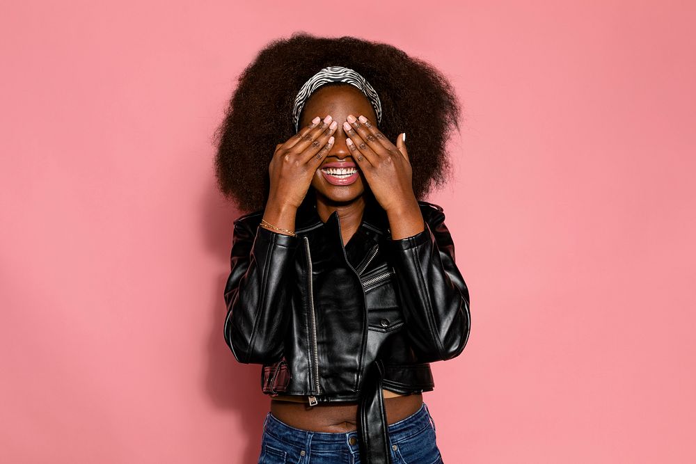 Shy woman covering her eyes, pink background