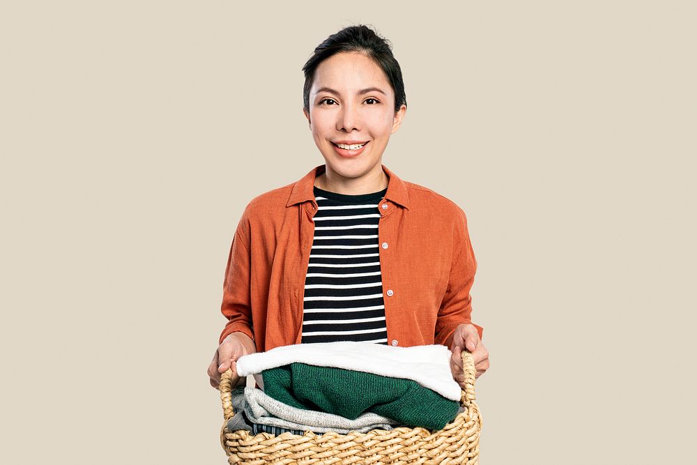 Cheerful Asian woman holding laundry basket