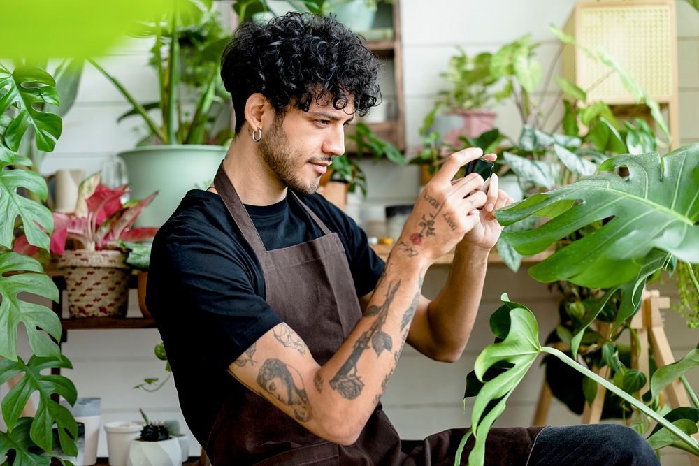 Plant shop worker takes a photo of potted plants