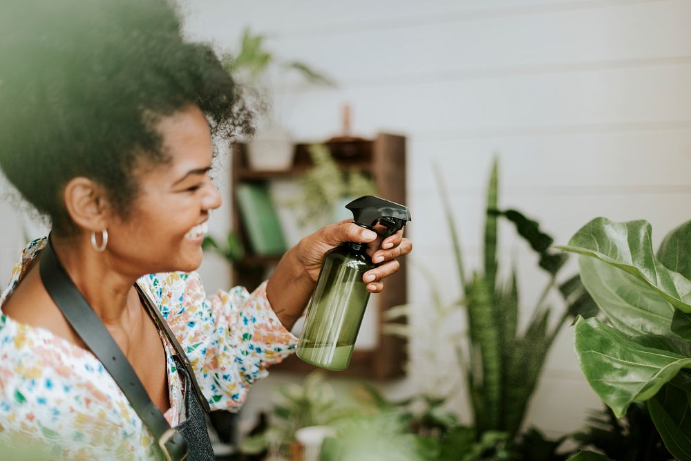 Small business worker misting plants with a water spray