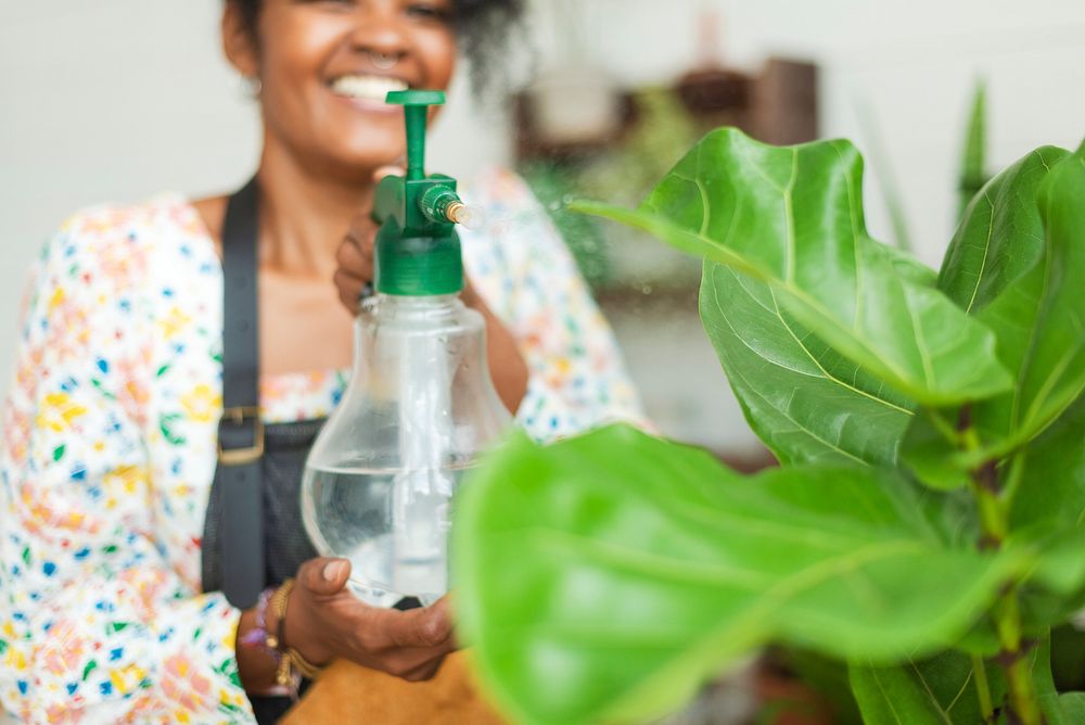 Woman misting plants with a water spray at a plant shop