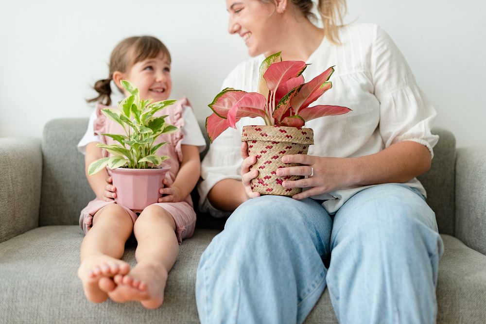 Kid and mother holding potted plants at home