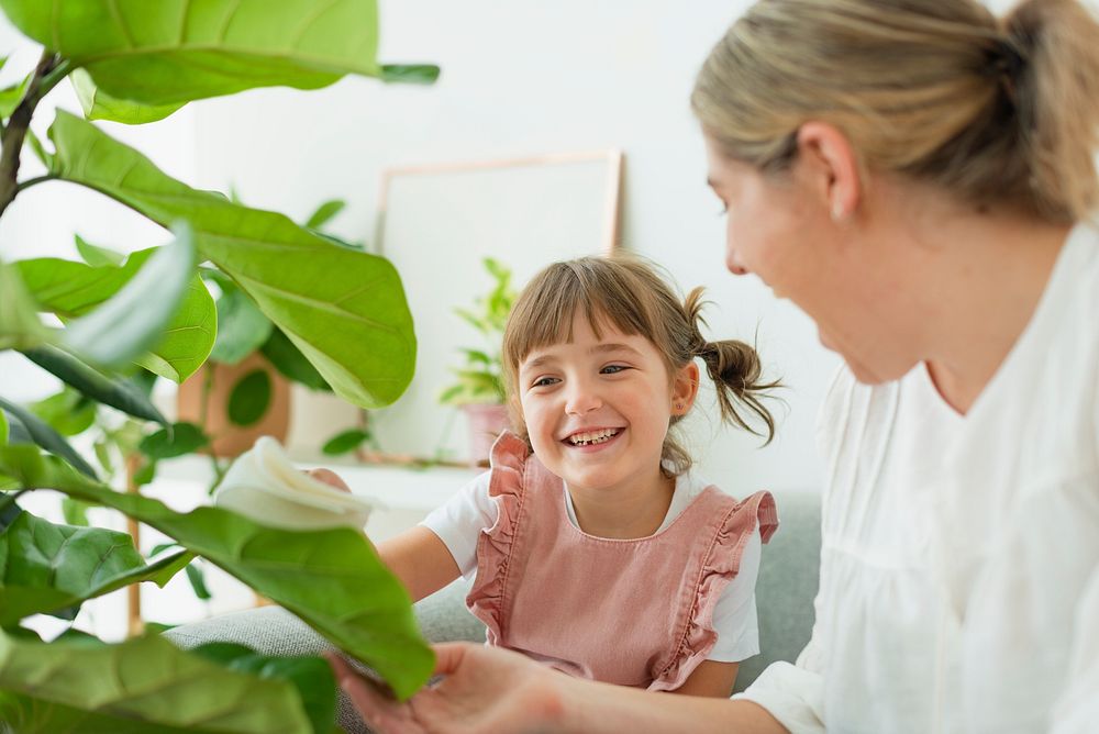 Happy little girl and mom at home with indoor plants