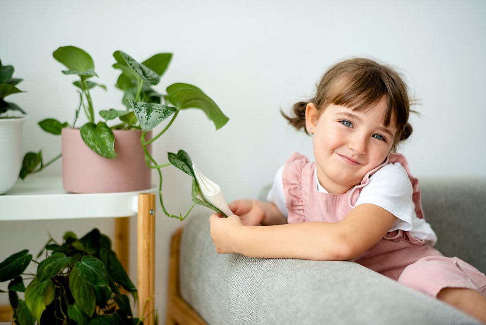 Happy little girl at home with indoor plants