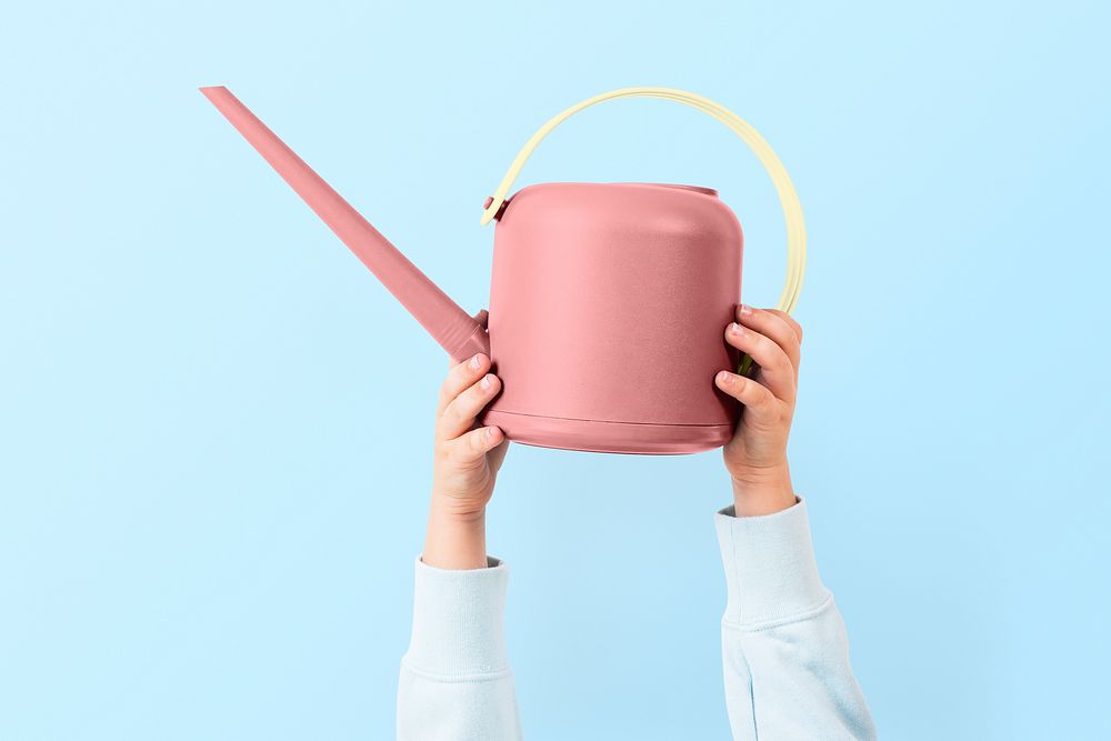 Hand mockup psd holding pink watering can gardening tool