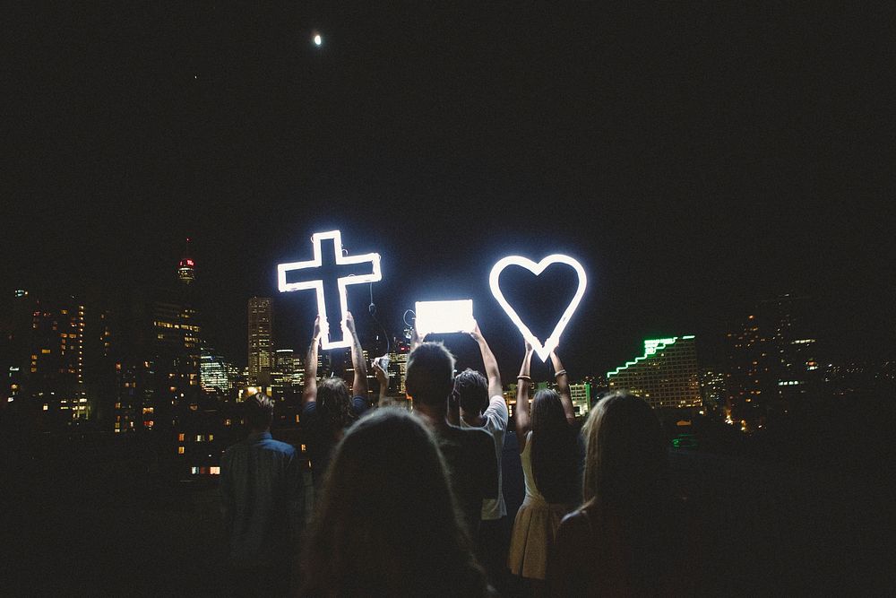 Man and Lady Raising Cross Heart Led Light Photo during Night Time. Original public domain image from Wikimedia Commons