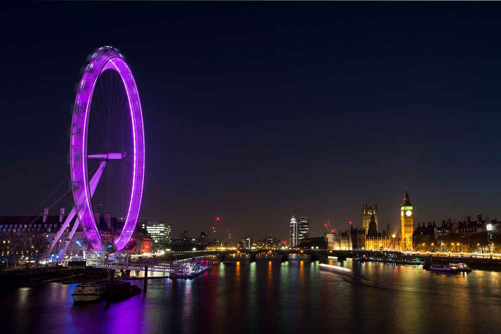 The purple-lit London Eye, the river Thames and the Palace of Westminster at night. Original public domain image from…