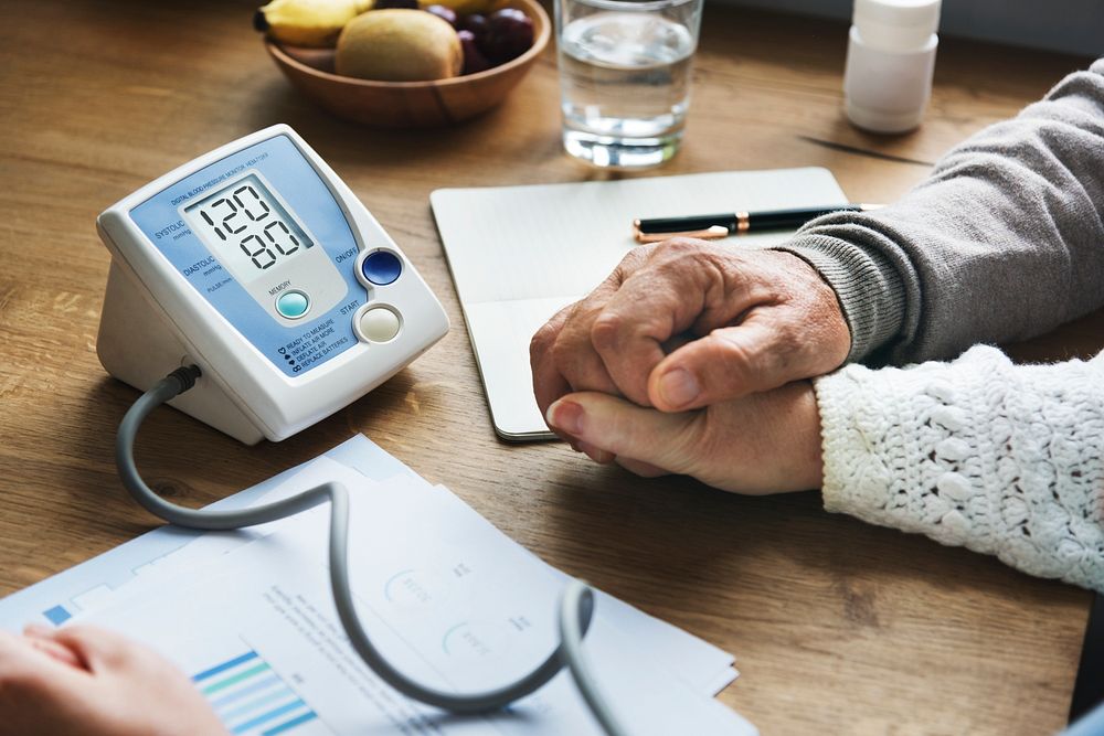 Blood pressure measure machine with senior people holding hands closeup