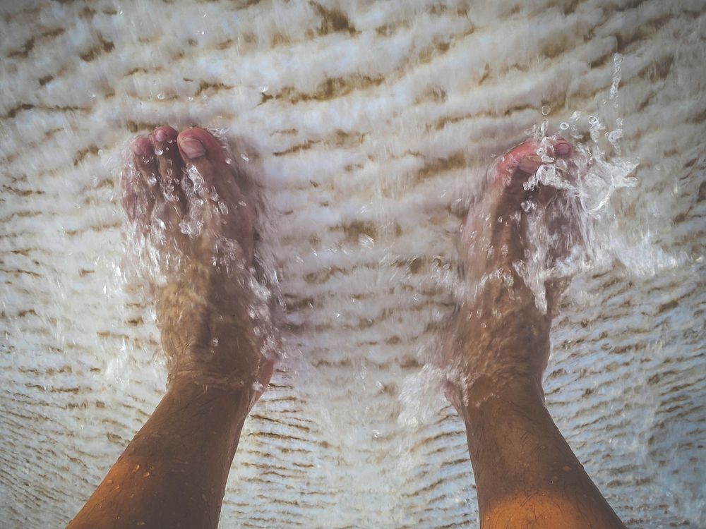 Water washes over his feet in the travertine pools. Pamukkale, Turkey. 