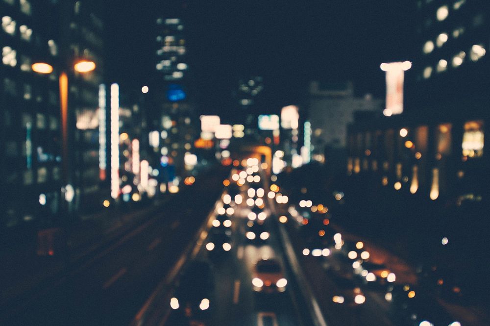 A blurry shot of a city street lit up by buildings and cars at night. Original public domain image from Wikimedia Commons