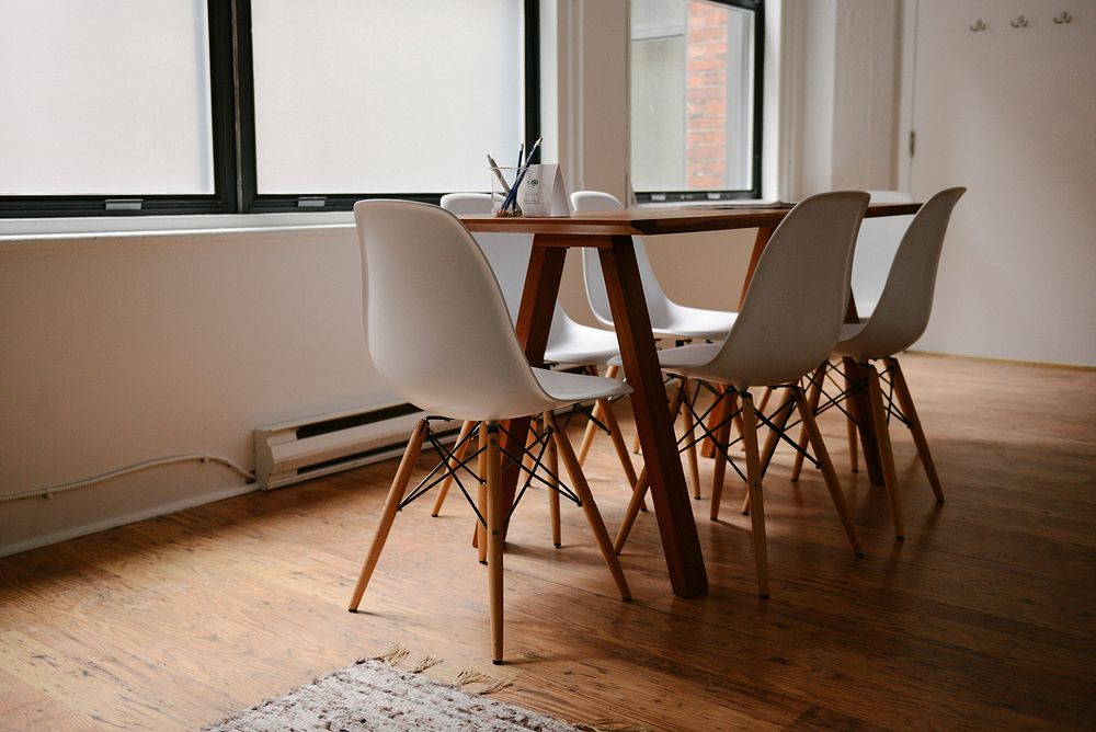 An interior of a meeting room stocked with modern wooden chairs and table in an office space. Original public domain image…