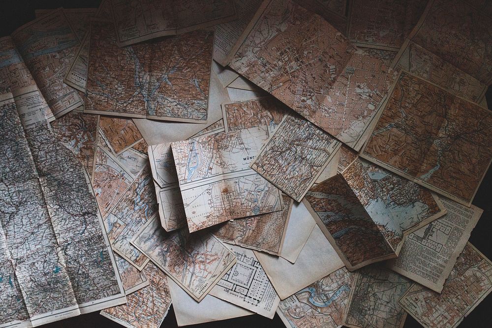 An overhead shot of a large collection of maps scattered on the floor. Original public domain image from Wikimedia Commons