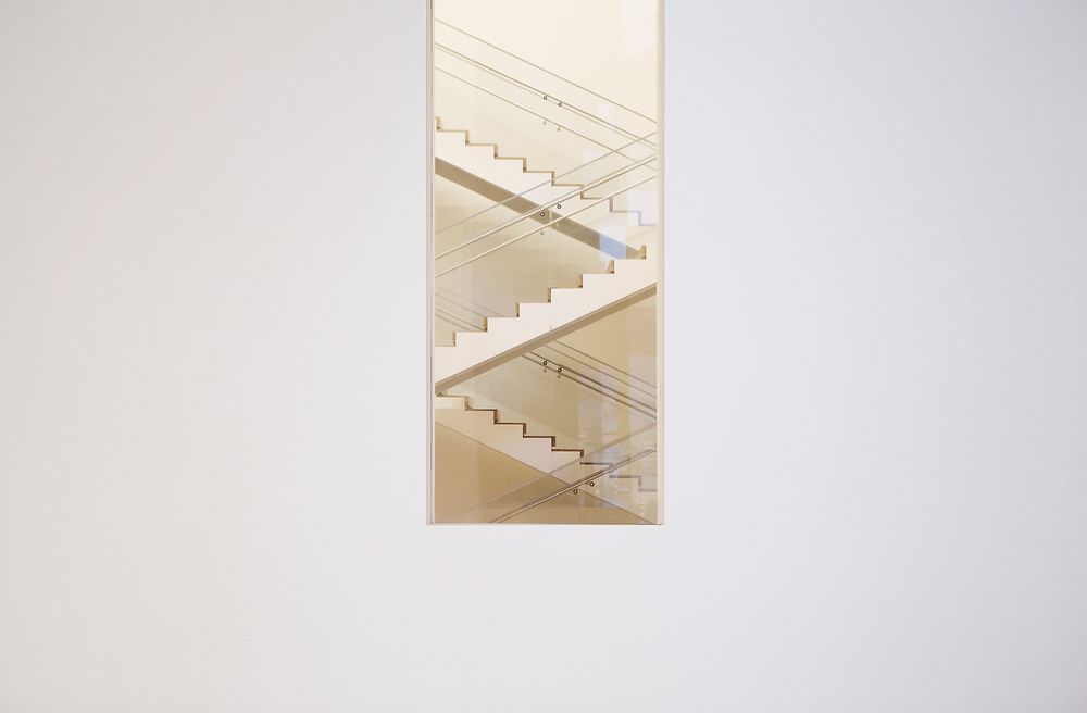 Long shot of zig zag staircase through window in white wall. Original public domain image from Wikimedia Commons