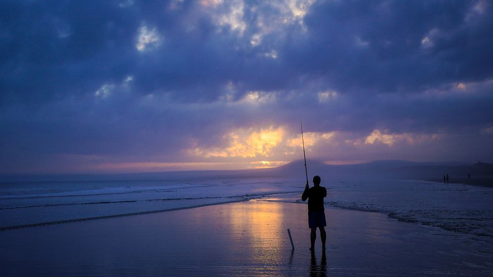 A silhouette of a fisherman fishing on a beach on Kiawah Island in the evening. Original public domain image from Wikimedia…