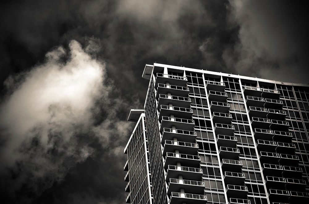 Black and white shot of urban condo apartment building from below with clouds, Orlando. Original public domain image from…