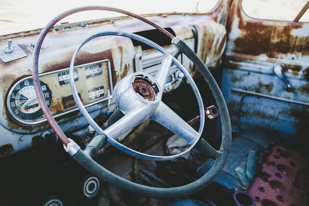 Steering wheel and speedometer in a rusty, abandoned classic car. Original public domain image from Wikimedia Commons