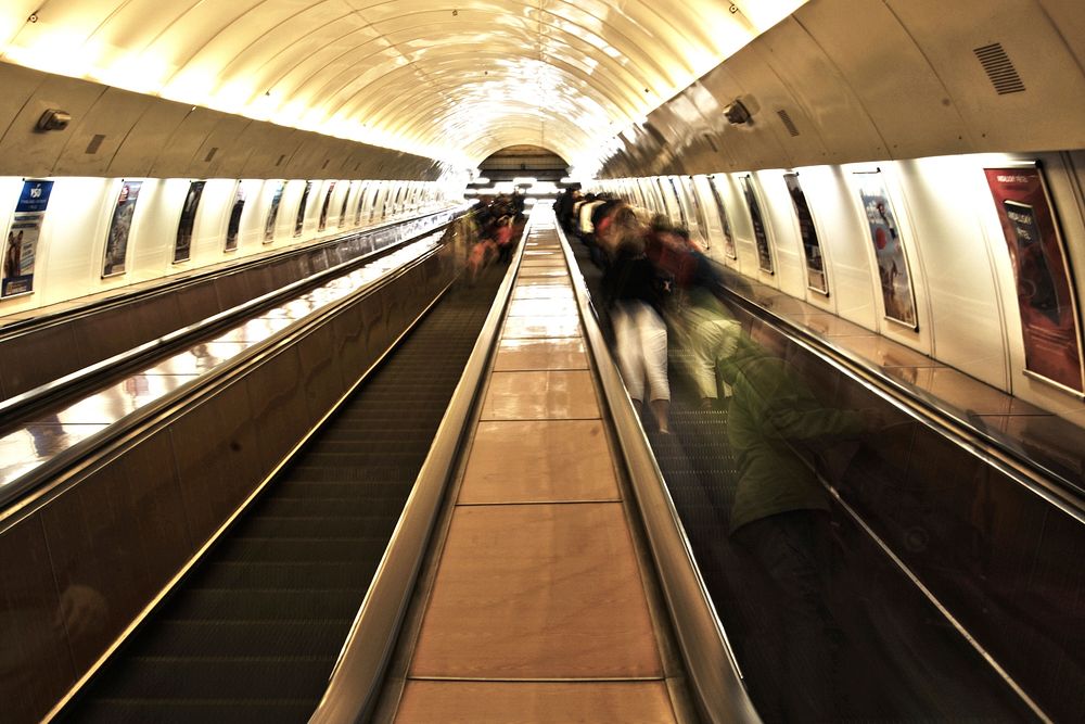 Inside a bright metro tunnel with escalators. Original public domain image from Wikimedia Commons