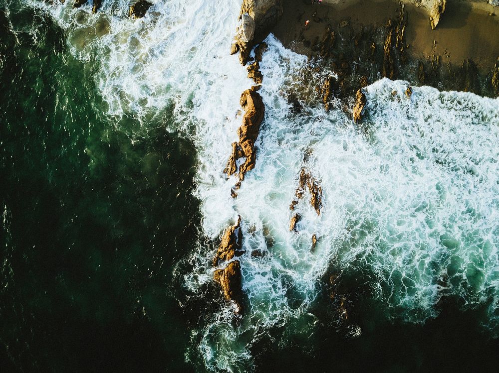Drone view of the ocean washing on the cliffs at Corona Del Mar. Original public domain image from Wikimedia Commons