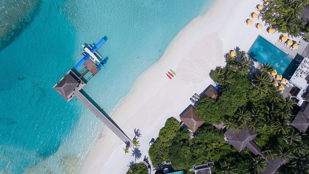 Drone aerial view of an airplane docked at the pier on the sand beach in Per Aquum Niyama. Original public domain image from…