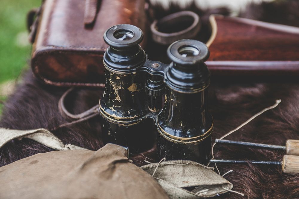 Black binoculars beside vintage bag. Original public domain image from Wikimedia Commons