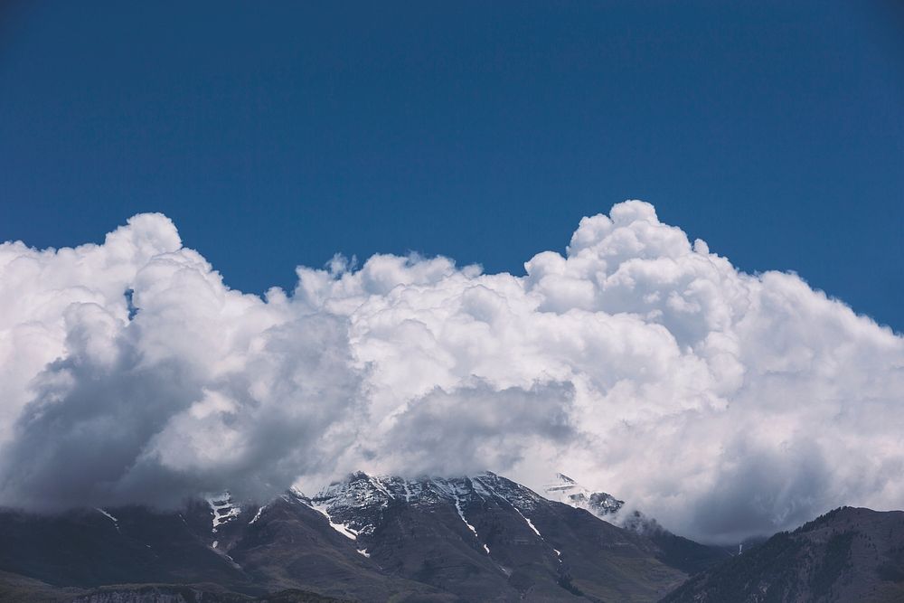 A massive white cloud over a snow-capped mountain ridge. Original public domain image from Wikimedia Commons