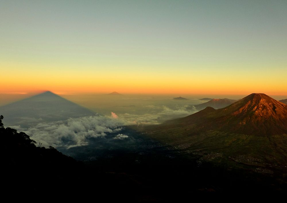 A volcano towering above a vast cloud-covered plain during sunset. Original public domain image from Wikimedia Commons