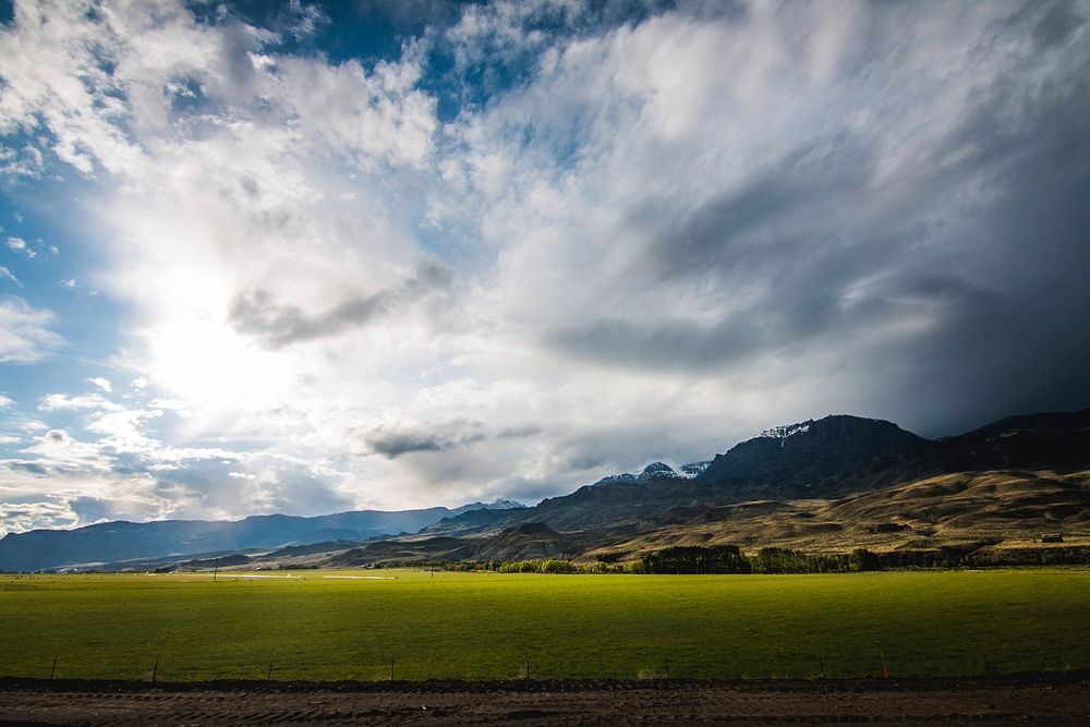 Tranquil pastures in a rural valley below snowy mountains on the horizon. Original public domain image from Wikimedia Commons