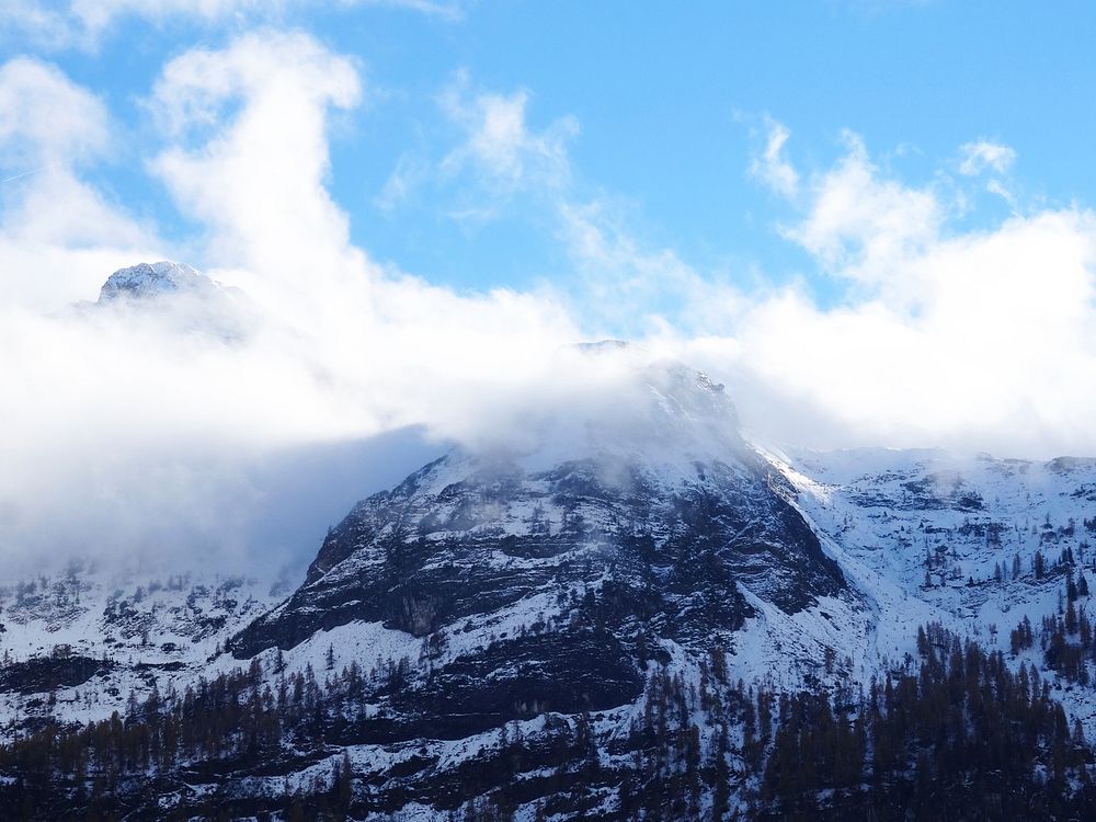 A snowy mountain peak enveloped in clouds. Original public domain image from Wikimedia Commons