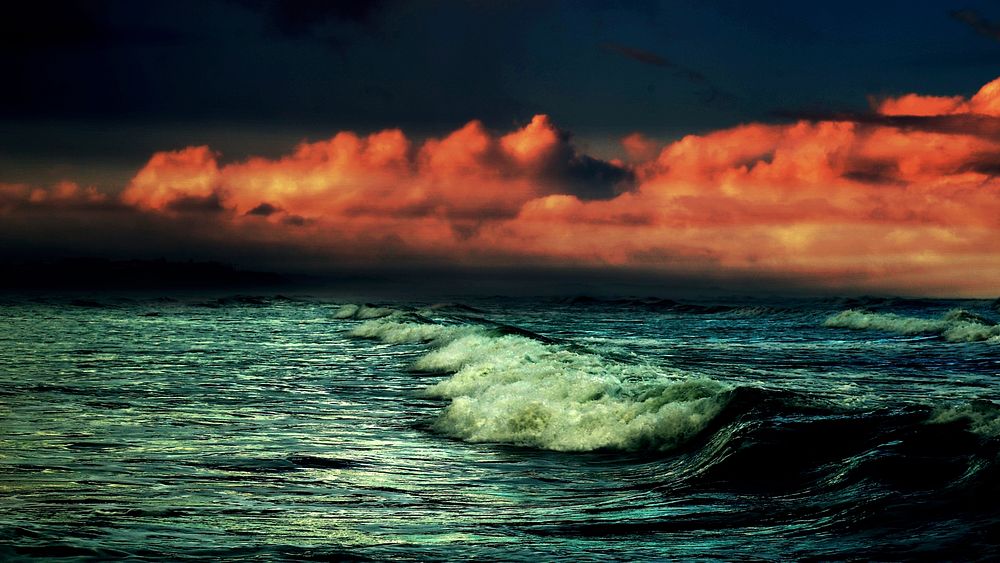 A dramatic shot of dark crashing waves under a red cloudy sky. Original public domain image from Wikimedia Commons