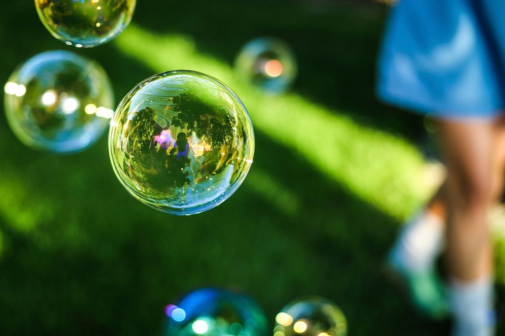 Round soap bubbles reflecting their surroundings on a sunny day. Original public domain image from Wikimedia Commons